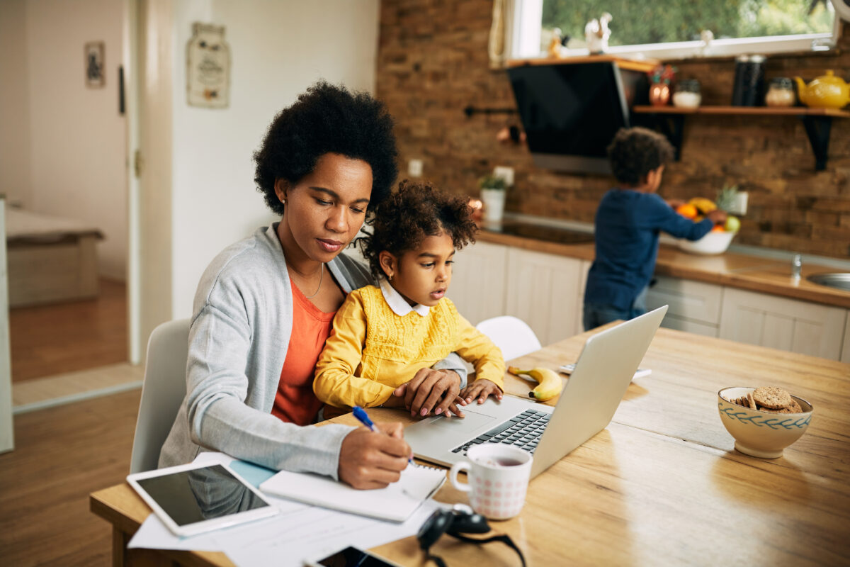 Mother with two kids on school break working at home.